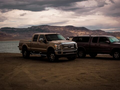 Two pickup trucks side-by-side in a rugged outdoor setting, highlighting their towing capacity and performance features.