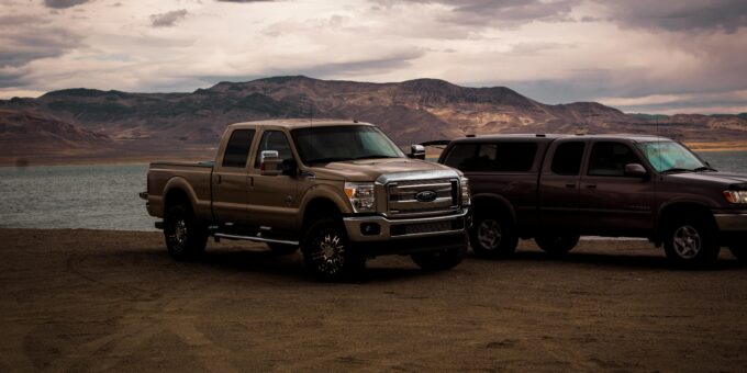 Two pickup trucks side-by-side in a rugged outdoor setting, highlighting their towing capacity and performance features.