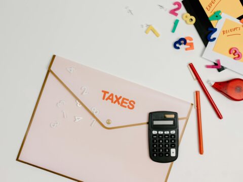 A person using a calculator and reviewing a car loan document, highlighting monthly payment calculations.